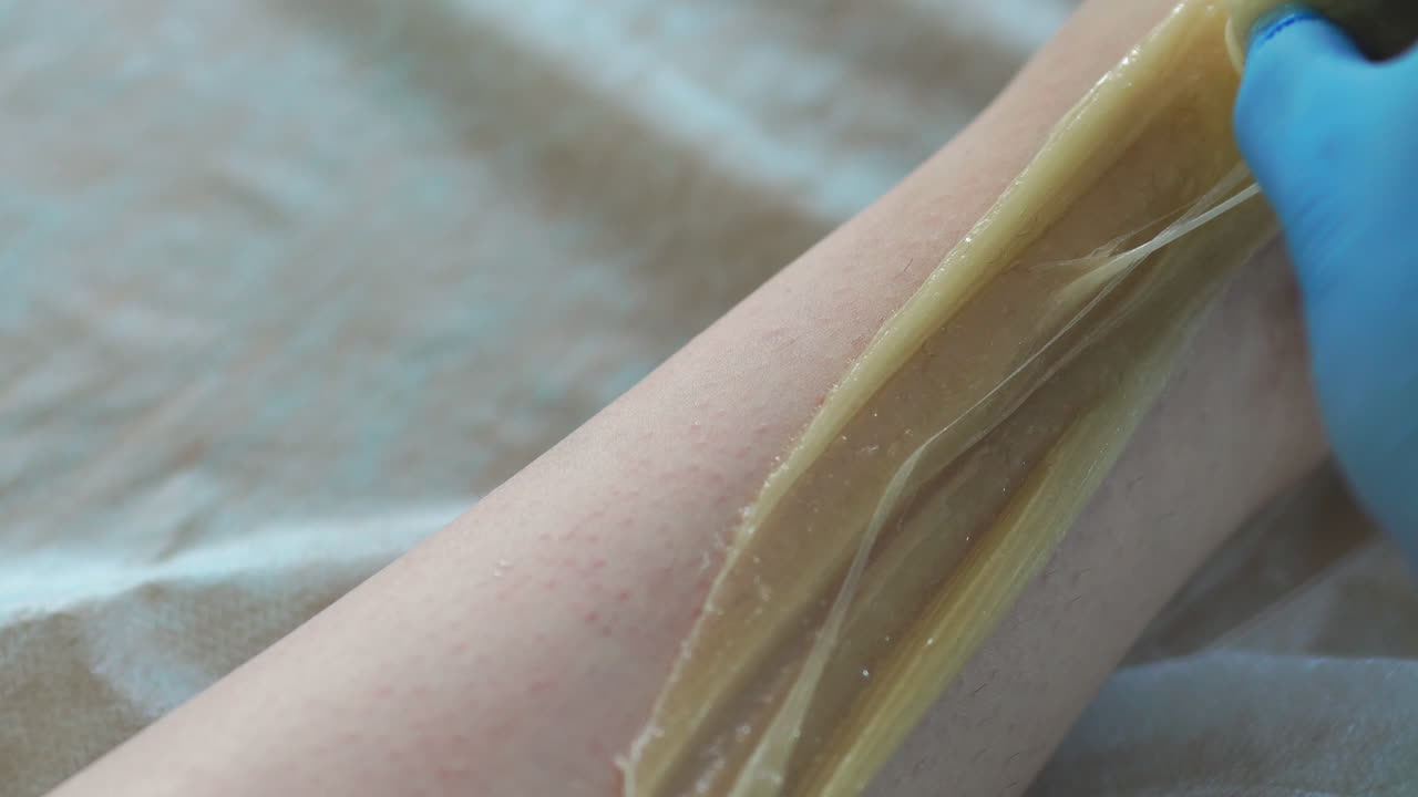 la chica habla por teléfono y sonríe durante la depilación de las piernas en el salón de belleza. depilación de las piernas con azúcar. clouse-up