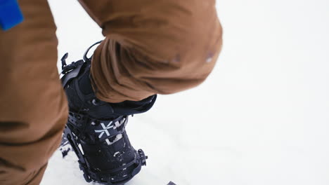 splitboarder locking in boot and safety checking in white powdery snow