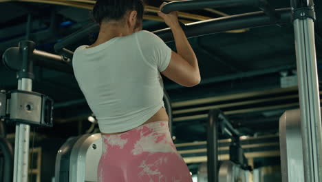 chica asiática haciendo chin ups en un gimnasio