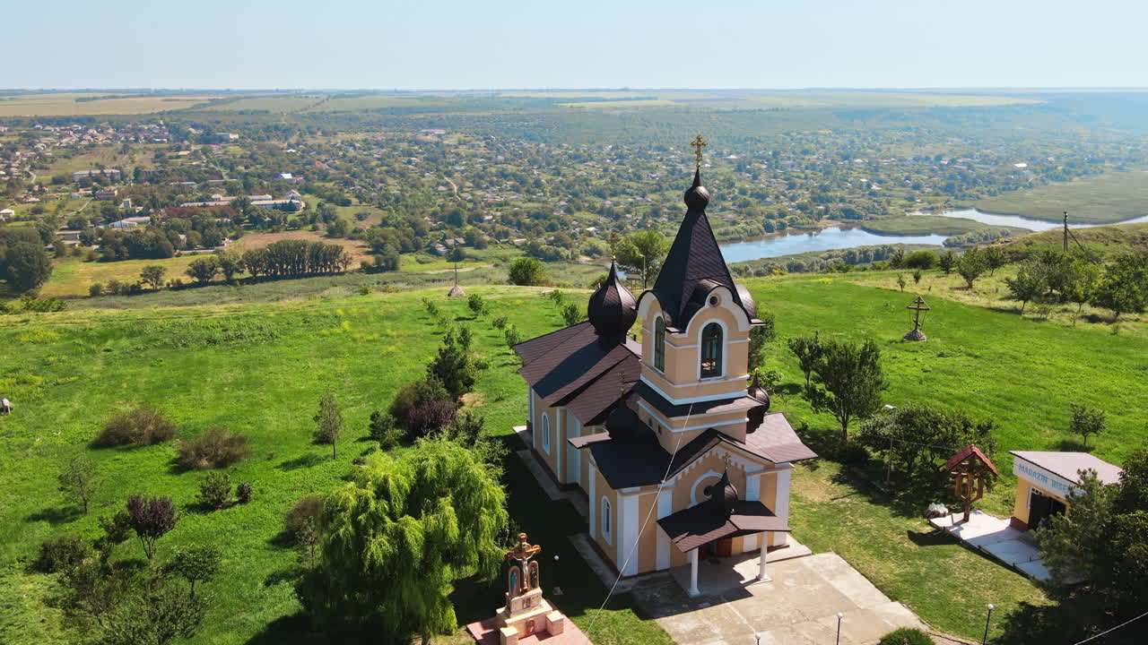 Aerial drone view of a church, located near a valley with river in Moldova. Village on the background