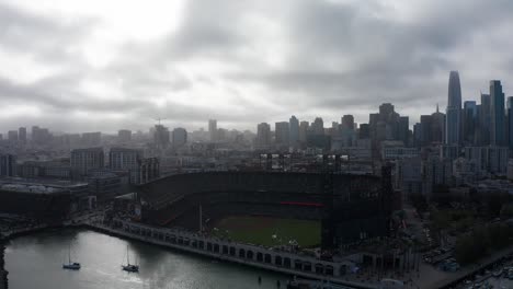 aerial wide reverse panning shot of oracle park with downtown san francisco in the background on a foggy day