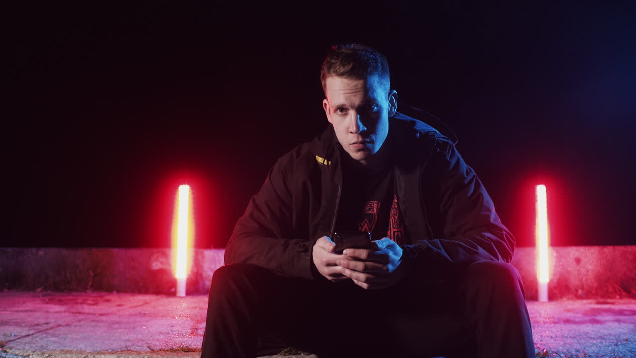 Man Sitting and Looking at Smartphone at Night