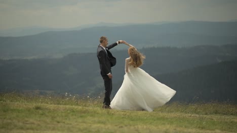 Groom-with-bride-having-fun-on-a-mountain-hills.-Wedding.-Bride-is-dancing