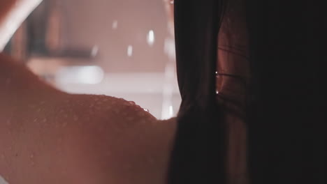 water drops on woman skin in shower cabin closeup. smooth body and wet hair of lady standing under sprays in bathroom. bodywash procedure at home