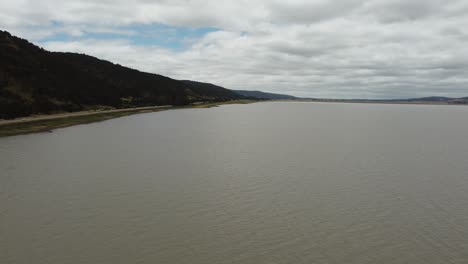 drone flying over a muddy lake motorway and a mountain in the background