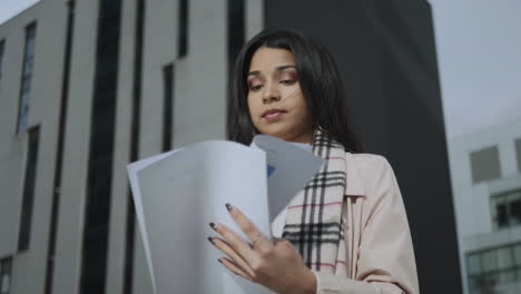 serious girl reading documents on street. business woman working with papers