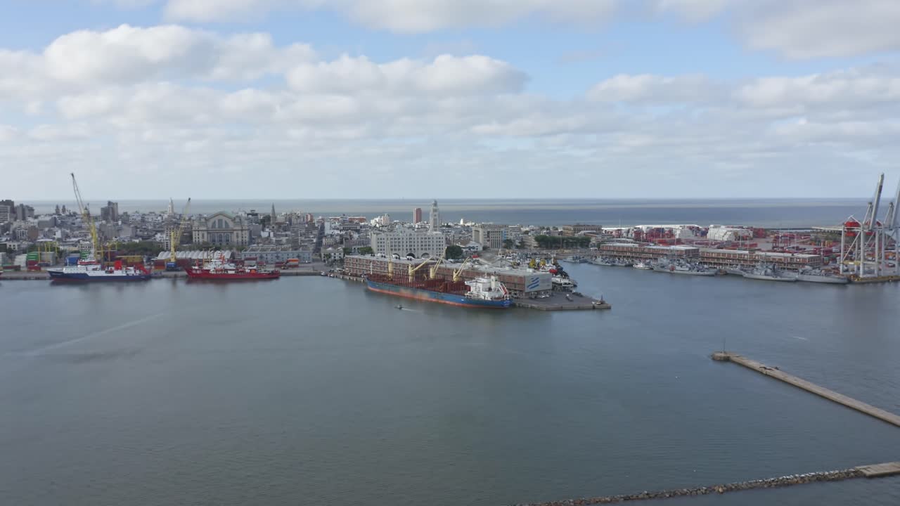 Uruguay capital city Montevideo. Right panning aerial drone view of barrio Ciudad Vieja and container terminal, seen from above the port. Calm cloudy weather