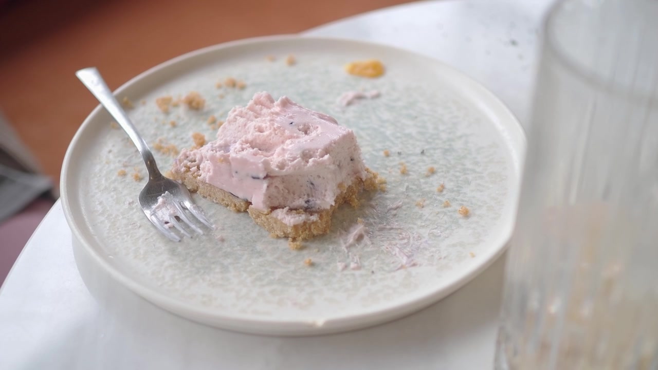 Kousek růžového bobulového cheesecaku na talíři