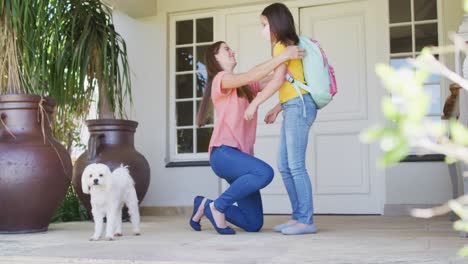 Caucasian-mother-embracing-and-hugging-her-daughter-wearing-face-mask-outside-the-house