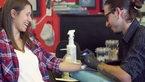 una mujer se sienta en una silla con un tatuaje en un salón filmado en r3d