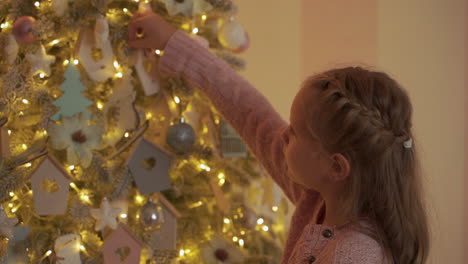 niña decora el árbol de navidad con bolas, luces y adornos en casa