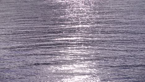 sparkling sun reflections on ocean surface from moving boat - slow motion