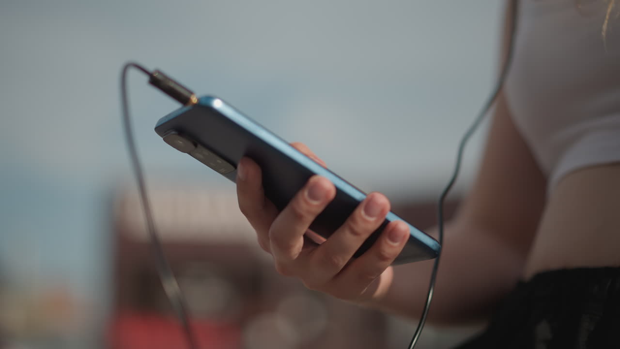 Donna prova la musica, ragazza collega le cuffie mentre si gode una rilassante sessione di allenamento di street dance estiva, giovane donna all'aperto testa la sua configurazione musicale per una sessione di allenamento di street dance estiva informale