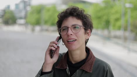 mujer sonriente hablando por teléfono celular al aire libre