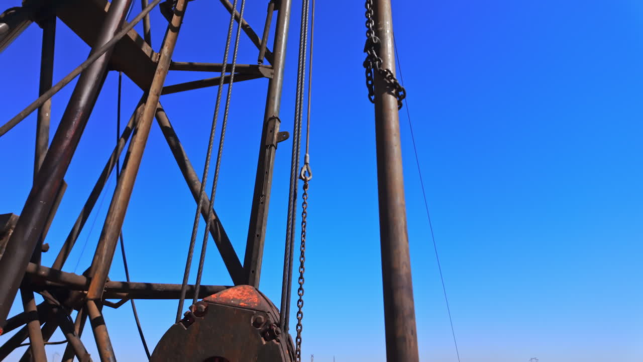 Metal rusty equipment at the boring site for oil production. High derrick for drilling process in the desert. Low angle view.