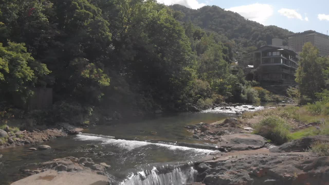 Ripresa aerea che si innalza lentamente sul fiume e risale la corrente nella famosa città termale onsen di Jozankei, Hokkaido, Giappone.