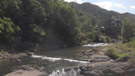 toma aérea que se eleva lentamente sobre el río y va río arriba en jozankei, la famosa ciudad termal onsen de hokkaido, japón