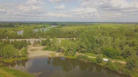 newly-wedded-couple-on-green-bank-of-calm-lake-upper-view