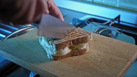 knife cutting toasted whole grain sandwich with boiled eggs and mayonnaise filling