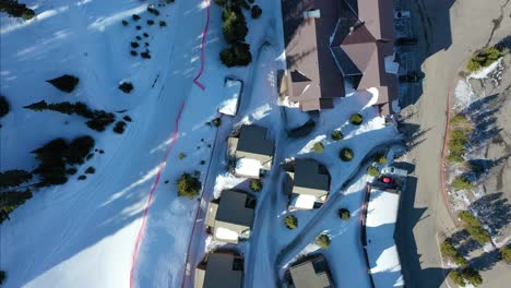 bird’s eye drone view of big sky montana winter condos blanketed in snow, framed by pine trees and blue mountain shadows in the distance—ideal for holiday travelers seeking peace and beauty