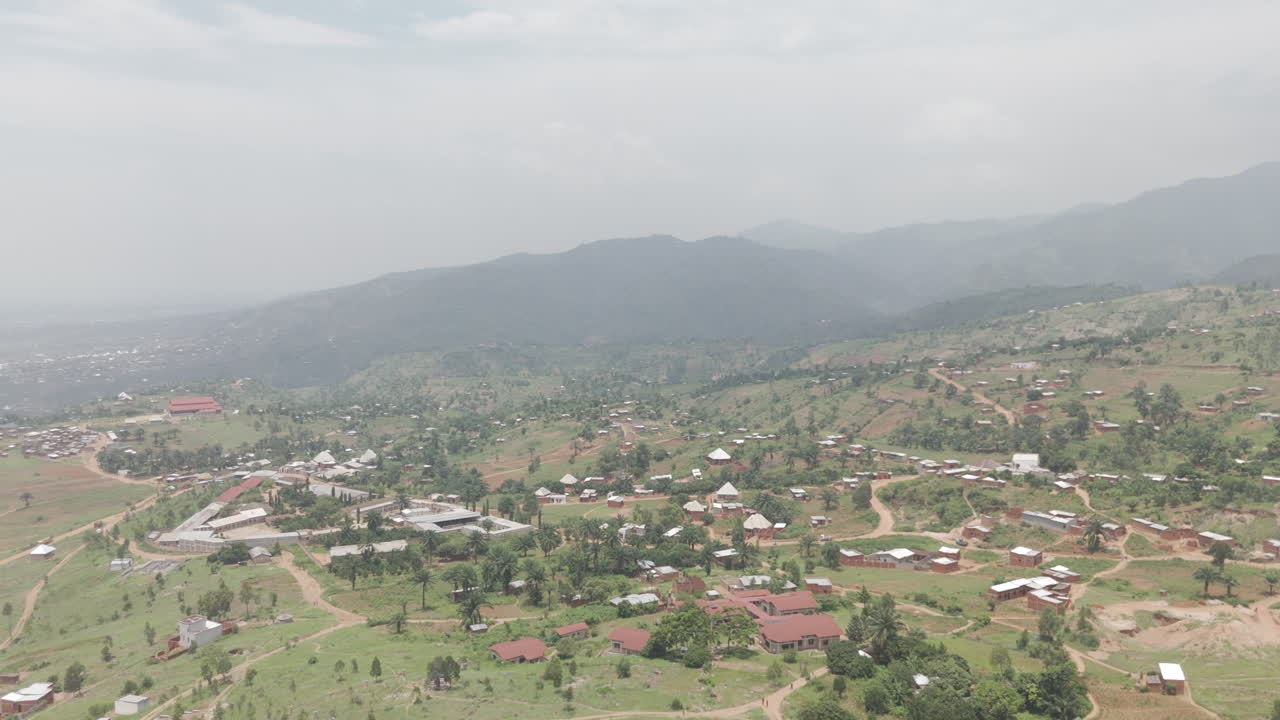 Drone shot the rural town of Kimina Bujumbura Burundi Africa on a warm day with houses on the ground and Lake Tanganyika in the background behind the hills LOG
