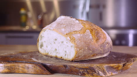 sourdough bread loaf on a kitchen table with man walking in blurry background - close up, slider shot