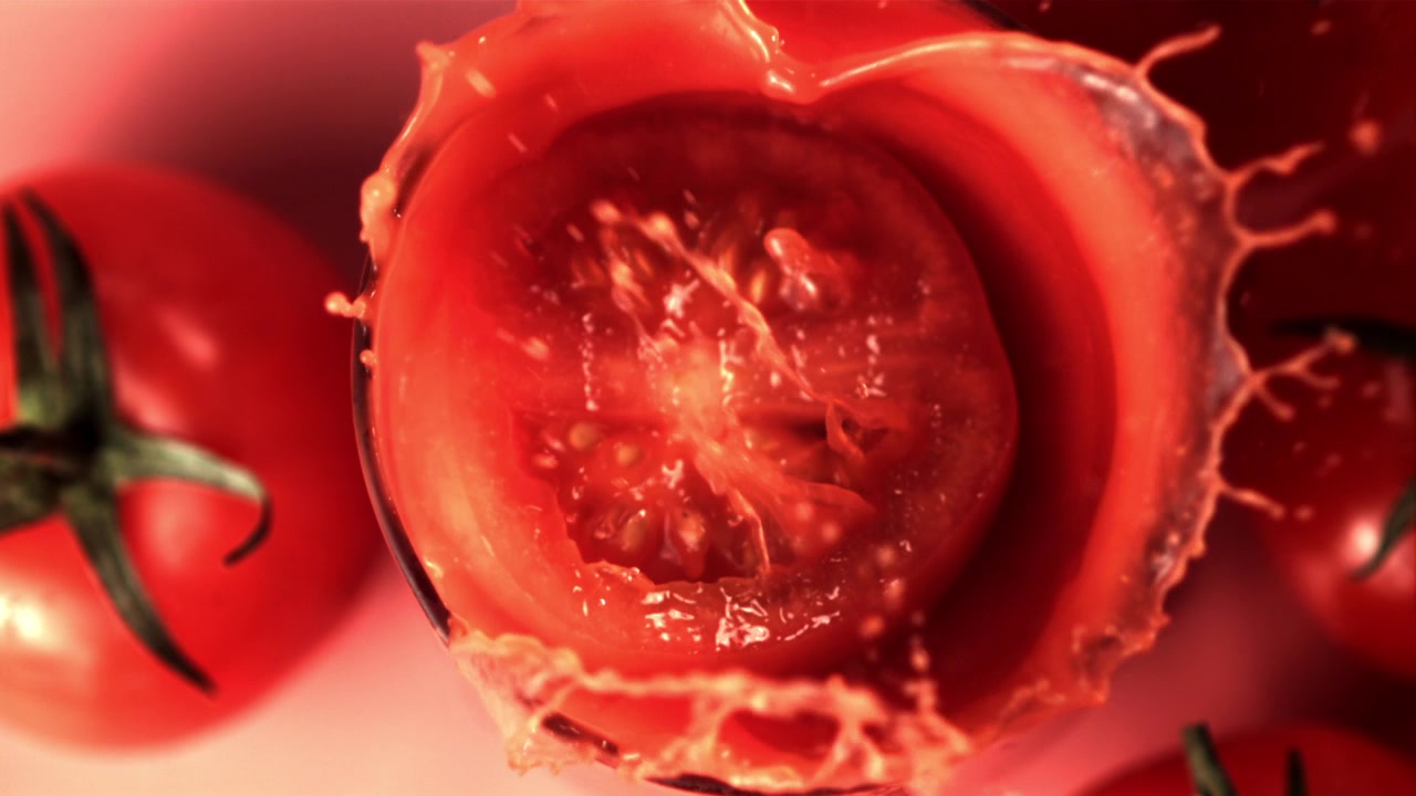 Slow Motion Half Tomato Splashing into a Glass of Red Juice