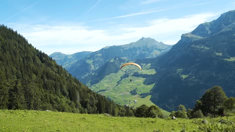 paraglider flying down the mountain in the swiss alps