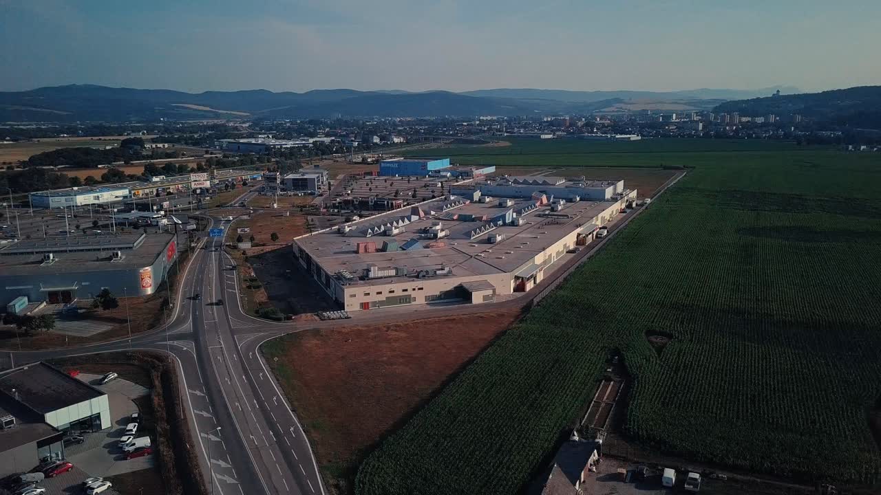 Drone shot above a shopping center in Trenčin, Slovakia, surrounded by fields, with the city in the background