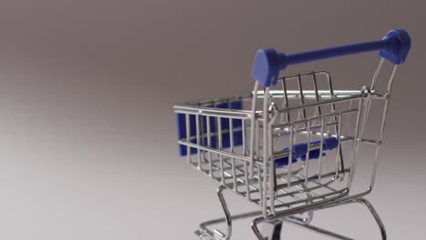 un carrito de compras azul vacío sobre un fondo gris