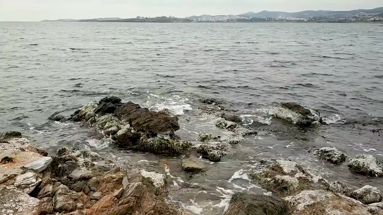 Costa rocciosa con piccole onde in inverno, cielo con nuvole, Lavrio Grecia