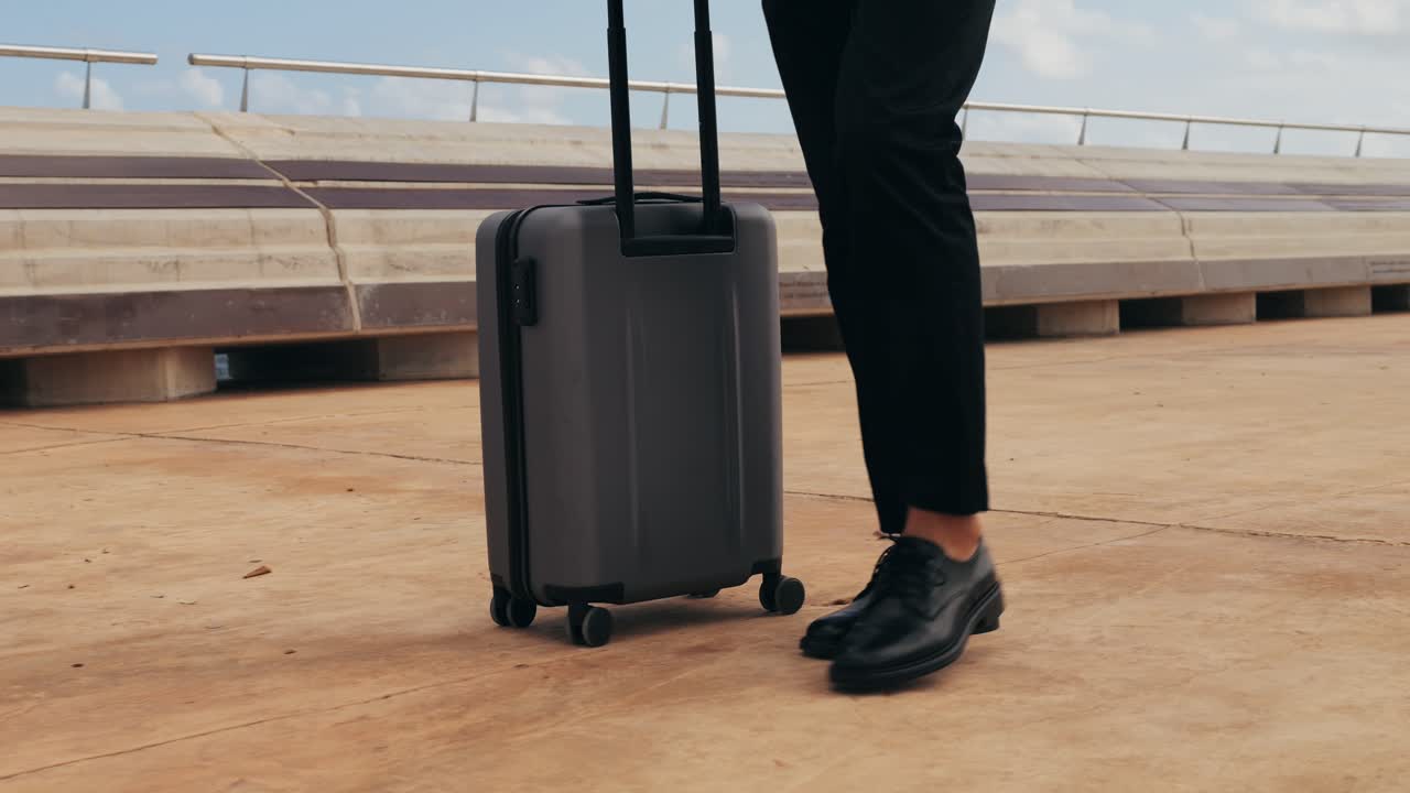 Toerist met kofferbagage in Spanje, een reiziger met bagage en een kostuumjas op een zakenstraat op weg naar een hotel, kantoor, luchthaventerminal, genietend van de levendige sfeer