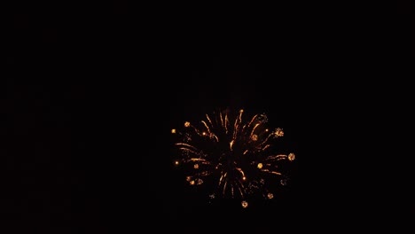 Fireworks-exploding-going-off-in-the-dark-of-night-as-drone-is-flying-close-to-the-show,-then-flys-back-to-reveal-lake-with-colorful-explosive-reflections-in-water