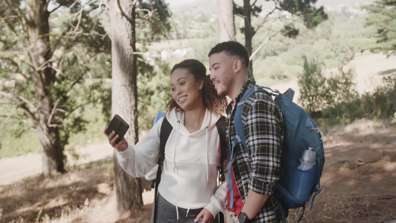 feliz pareja afroamericana usando un teléfono inteligente y tomando selfies en el bosque, cámara lenta