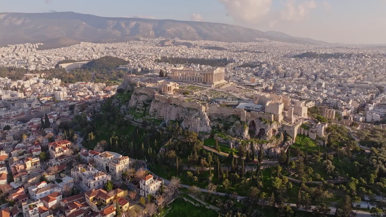 Ripresa cinematografica in movimento con drone dall'Antica Agorà verso l'Acropoli al tramonto ad Atene, in Grecia. La luce dorata, le antiche rovine e lo skyline storico creano una scena epica per i viaggi, ecc.
