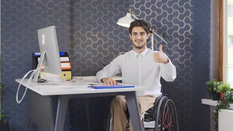 Disabled-man-works-in-the-office-and-looks-at-the-camera,-smiling.