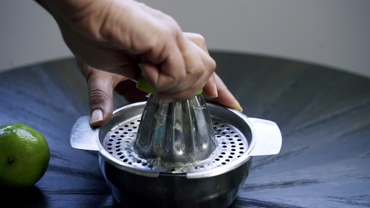 Nice shot of woman juicing a lime using a traditional steel juicer lemon lime citrus vitamin c