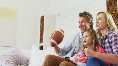Lächelnde-Familie,-Die-Fernsieht,-Während-Sie-Popcorn-Im-Wohnzimmer-4k-Isst
