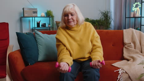 Abuela-Mayor-Haciendo-Ejercicios-De-Fitness-Con-Pesas-Y-Pesas,-Entrenando-Fuerza-En-Casa