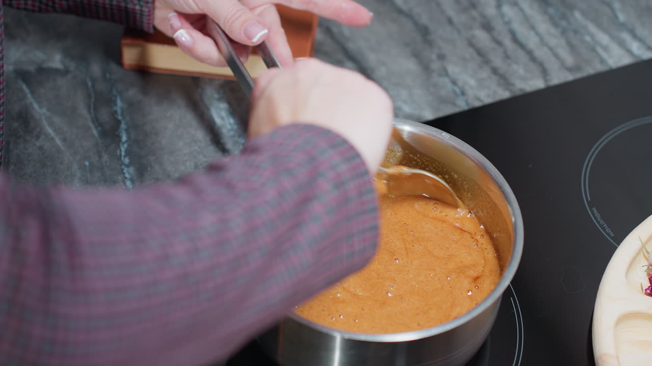 primer plano de una mujer cocinando, agitando sopa burbujeante mientras sostiene el mango de la olla en la estufa, el rico plato hirviendo mezcla ingredientes a medida que el vapor se eleva en una cocina acogedora