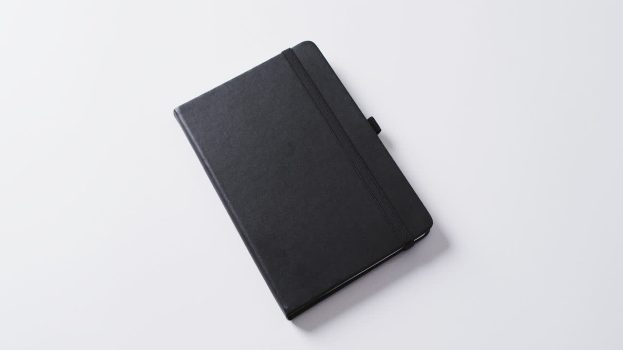 Close up of closed black notebook with copy space on white background in slow motion
