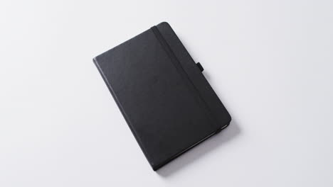 primer plano de un cuaderno negro cerrado con espacio de copia en fondo blanco en cámara lenta