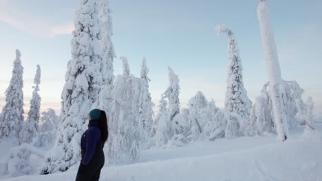 girl walking downhill observing beautiful snow covered winter wonderland in lapland, finland, arctic circle