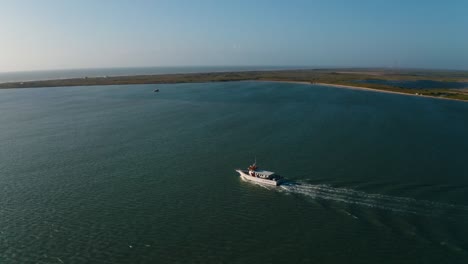 aerial drone pull away of fishing boat leaving harbor and heading out to see in south padre texas on hot summer day