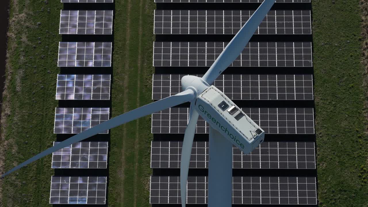 Vista aerea di una turbina eolica in rotazione sopra un parco di pannelli solari