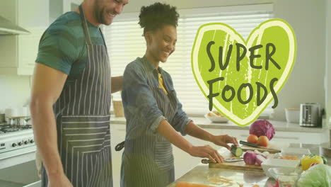 animation of super foods text over diverse couple preparing healthy meal in kitchen