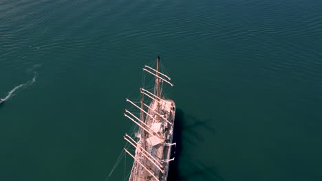 Overhead-flight-of-luxury-sailing-yacht-at-anchor-in-calm-glossy-sea-with-small-boats-and-tender-peaceful-scene-with-detail-of-decks-and-rigging