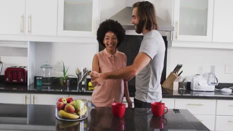 pareja de raza mixta bailando en la cocina en casa