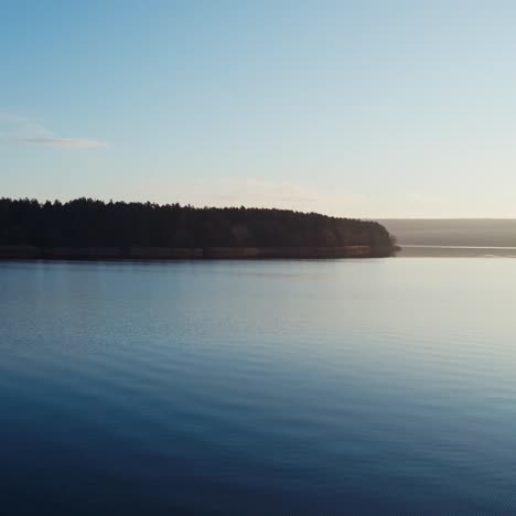 flying over blue water in the evening. beautiful calm river on trees background in nature at sunset. motion camera forward.