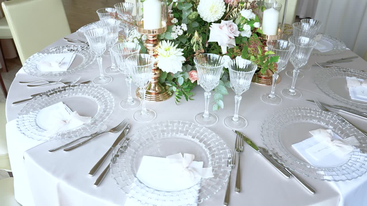 Beautifully arranged table setting with crystal glassware, floral centerpiece, and elegant cutlery. Ideal for weddings or upscale dining events. Soft lighting enhances ambiance